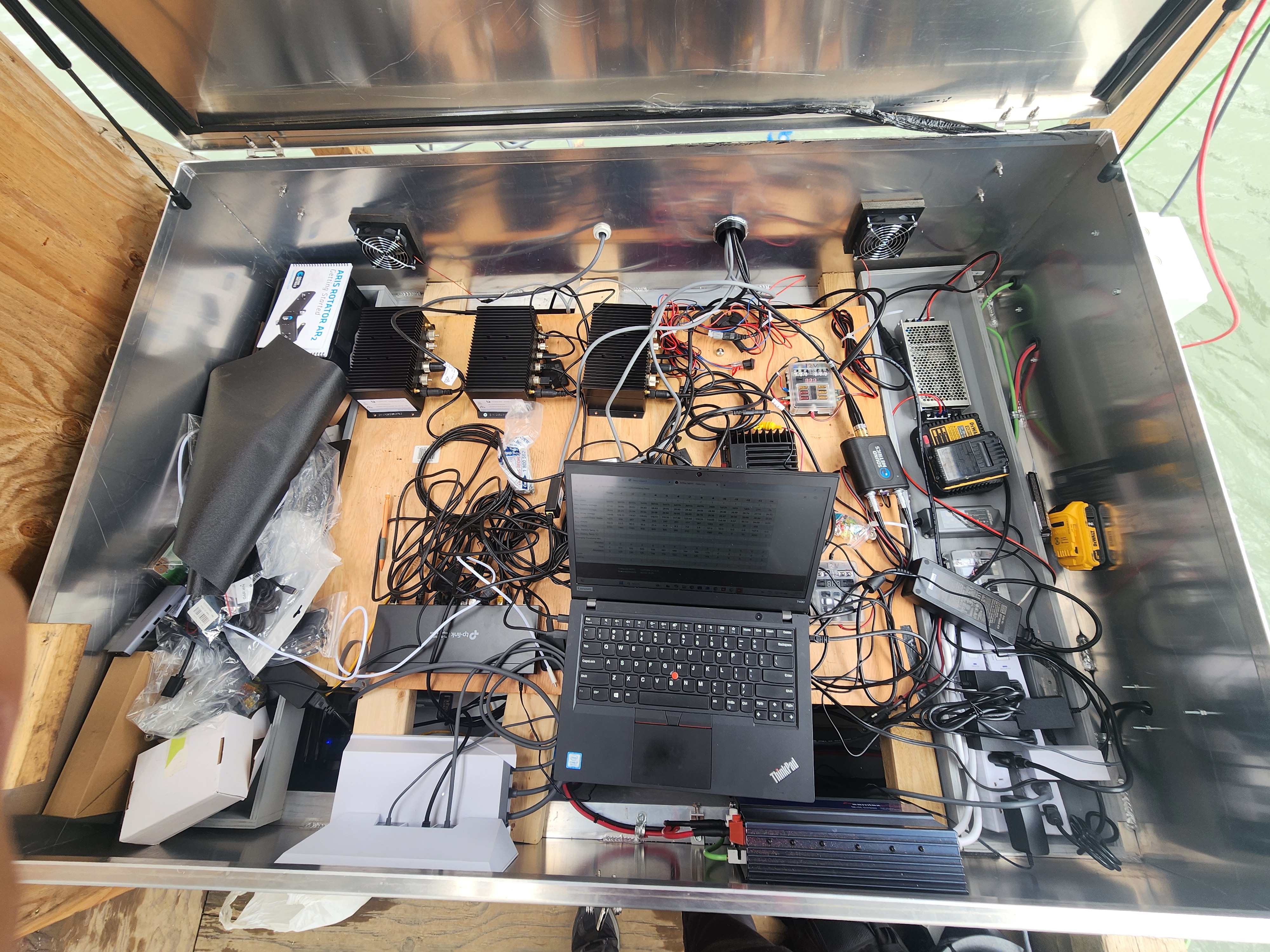 Open field enclosure containing SalmonVision computers, communications equipment, power components, cables, and a laptop.
